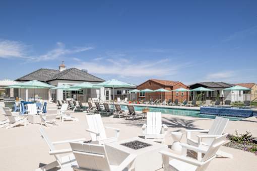A pool area with white chairs and umbrellas.