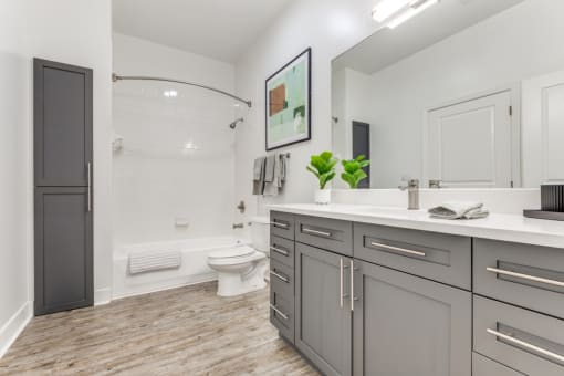 a bathroom with gray cabinets and a toilet and a shower