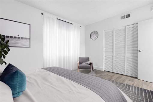 A modern bedroom with a large bed and a grey armchair.