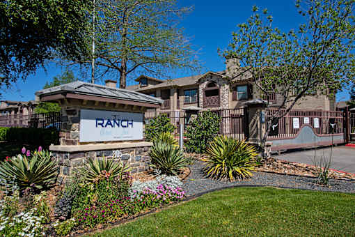 A ranch-style home with a stone sign in front.
