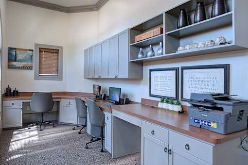 A well-lit office with a desk, chairs, and a printer.