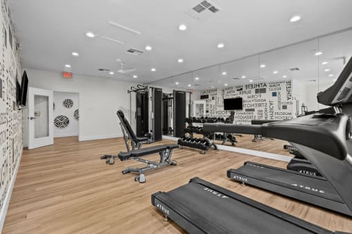 the gym with treadmills and other exercise equipment in a room with white walls