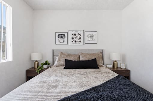 A bedroom with a bed, two lamps, and three pictures on the wall.