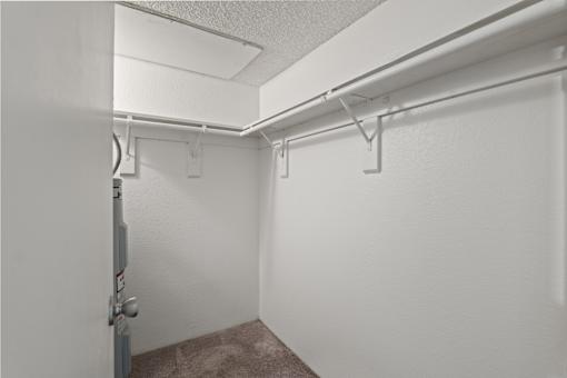 A white wall with a door and a white ceiling with a white pipe.
