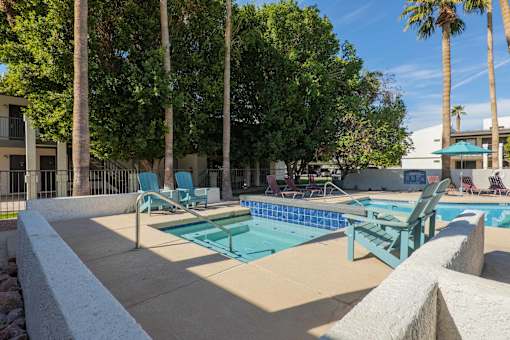 A pool surrounded by trees and chairs.
