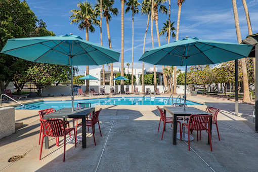 A poolside area with tables and chairs and umbrellas.