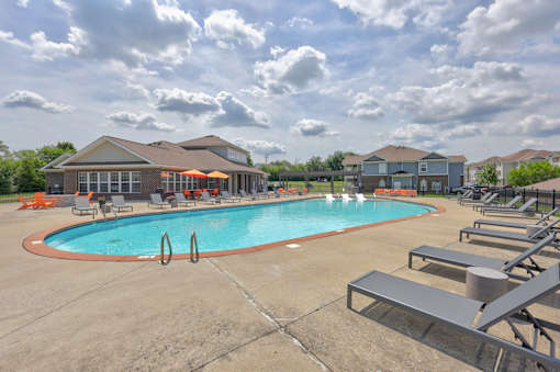 A large outdoor swimming pool surrounded by lounge chairs and umbrellas.