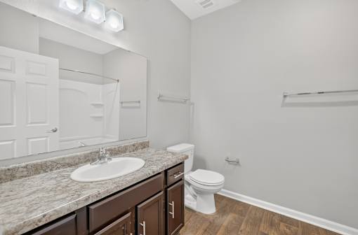 A white bathroom with a marble countertop and a toilet.
