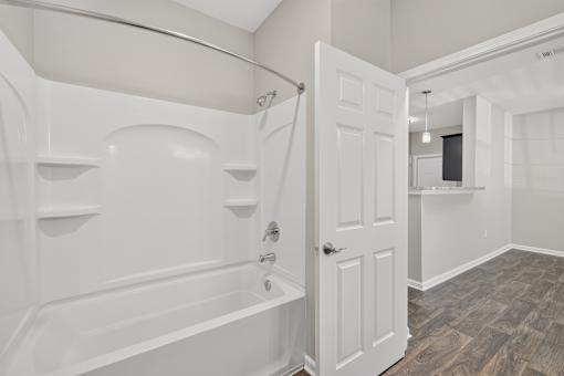 A white bathroom with a tub and a door.