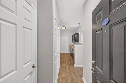 A hallway with a white door on the left and a black door on the right.