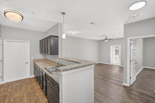 A kitchen with a sink, cabinets, and a countertop.