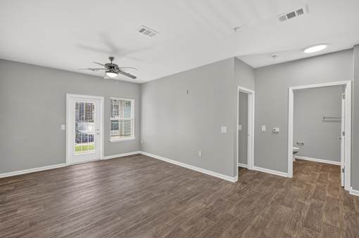 A room with a ceiling fan and wooden flooring.