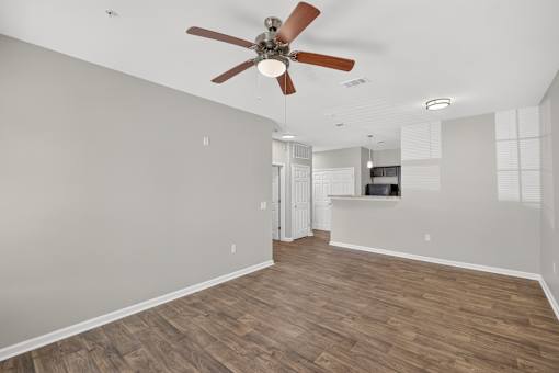 A room with a ceiling fan and wooden flooring.