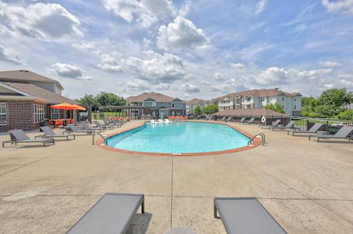 A large outdoor swimming pool surrounded by lounge chairs and umbrellas.