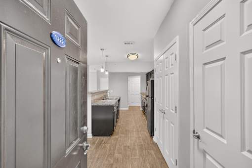 A hallway with a blue sign on the wall and white doors on the right.