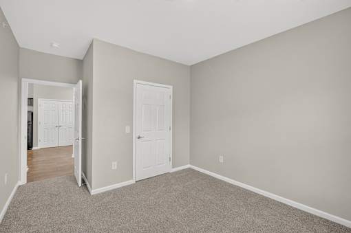 A room with a carpeted floor and two white doors.