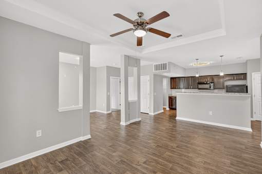 A spacious living room with a ceiling fan and hardwood floors.