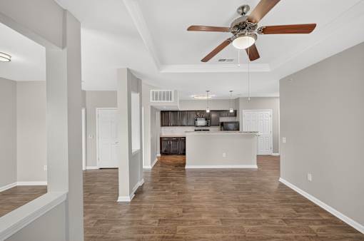 A spacious room with a ceiling fan and wooden flooring.