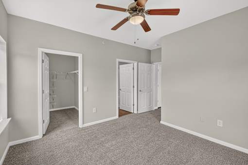 A room with a ceiling fan and two open doors.