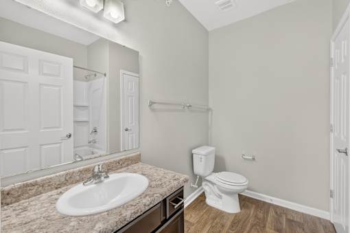 A bathroom with a sink, toilet, and mirror.