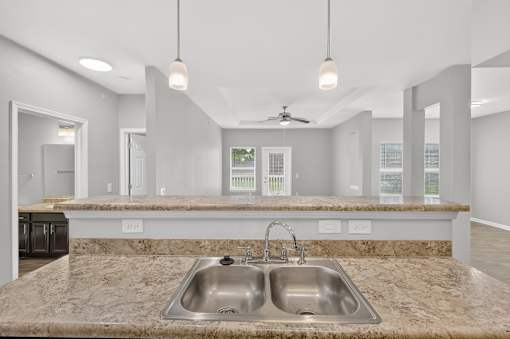 A modern kitchen with a double sink and marble countertops.