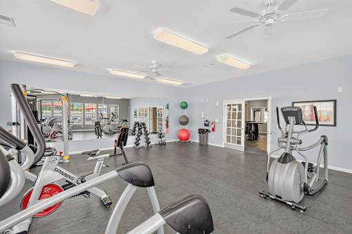 A gym with a variety of exercise equipment including treadmills, stationary bikes, and weight machines.