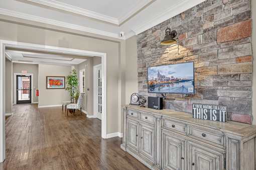 A hallway with a stone wall and a TV mounted on it.
