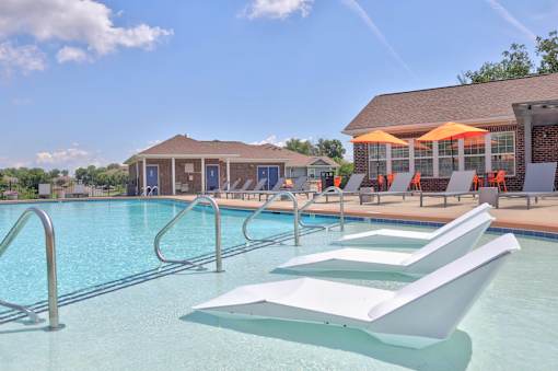 A pool with a white sun lounger in the foreground.