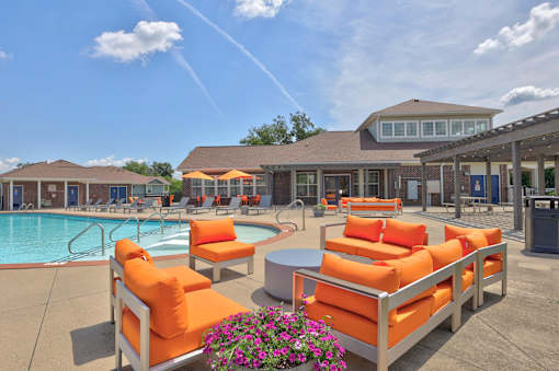A poolside area with orange chairs and a clear blue sky.