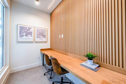 A room with a long wooden desk and two chairs.