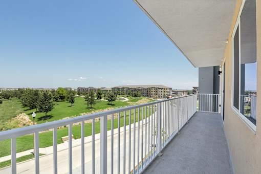 A balcony with a metal railing overlooks a green landscape.