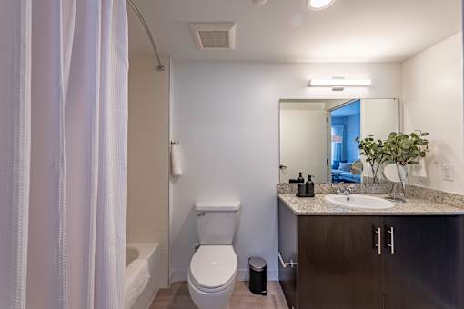 A bathroom with a toilet, sink, and mirror.