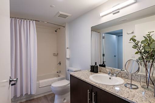 A bathroom with a white toilet, sink, and a shower with a white curtain.