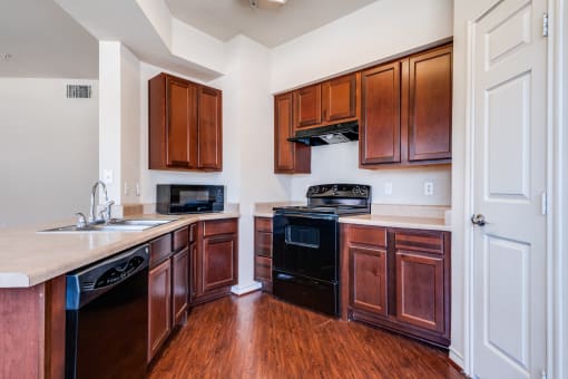 an empty kitchen with wooden cabinets and a black stove and oven