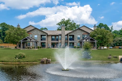 a fountain in the pond with a building in the background