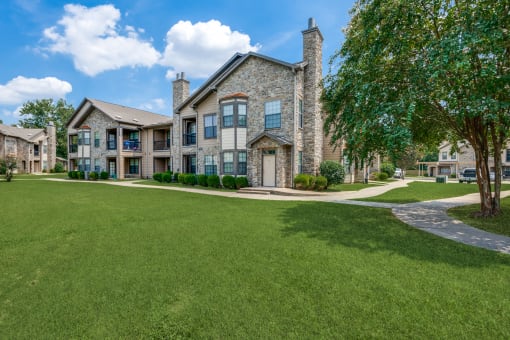 a large house with a green lawn and trees in front of it
