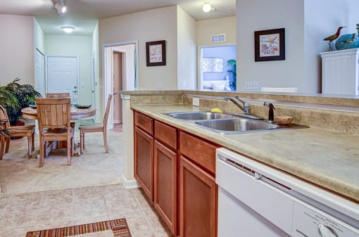A kitchen with a sink, dishwasher, and a table with chairs.