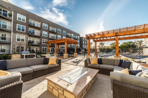 a patio with couches and a table in front of an apartment building and pool
