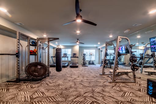 spacious gym with cardio machines and weights at the apartments
