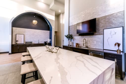 the kitchen has a large marble counter top and a tv