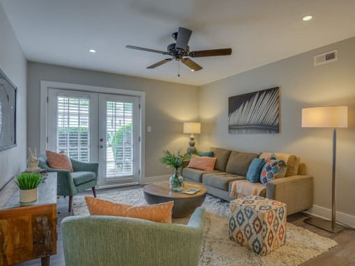 a living room with a couch and chairs and a ceiling fan