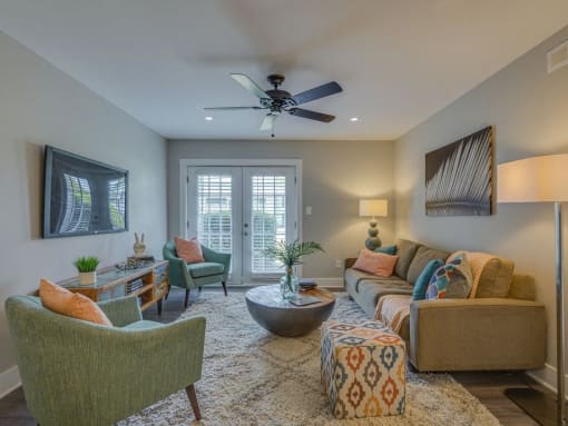 a living room with a couch and chairs and a ceiling fan