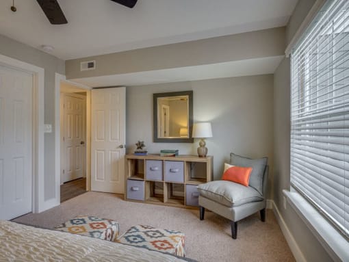 a bedroom with a chair and a desk with a mirror