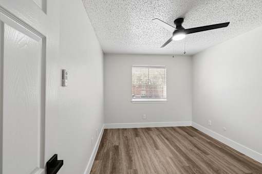 A room with a ceiling fan and wooden flooring.