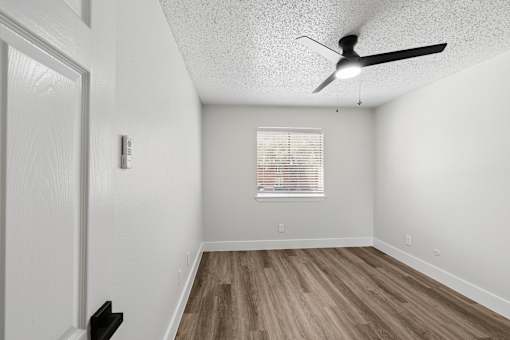 A room with a ceiling fan and a window with blinds.