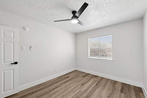 A room with a ceiling fan and a window with blinds.