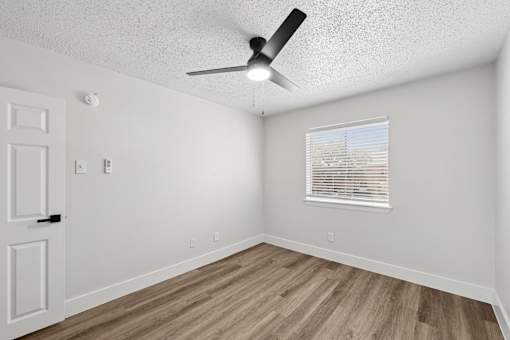 A room with a ceiling fan and a window with blinds.