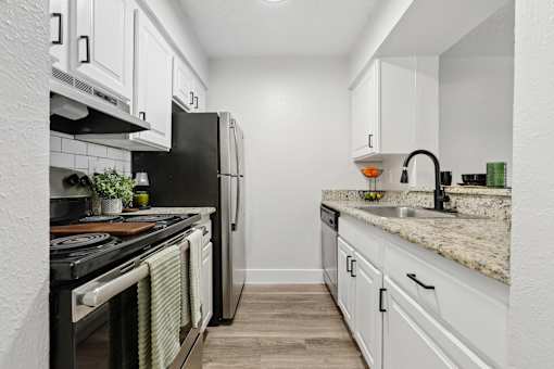 A kitchen with black appliances and white cabinets.