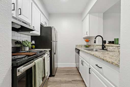 A kitchen with white cabinets and a black refrigerator.