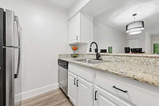A kitchen with a granite countertop and white cabinets.